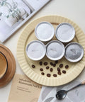 Plate displaying Aluminum Foil Lids for Reusable Coffee Pods, 62mm Seals for Nespresso VertuoLine, with coffee beans and drink