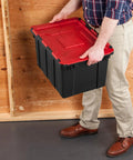 Haul Heavy Loads With Ease Using These Tough As Nails 12 Gallon Storage Totes With Secure Lids For Garage Organization Stackable Heavy Duty Crates Featuring Tie Down Grommets In A Rock Solid 12 Pack Bundle with a person holding a black and red plastic tote.