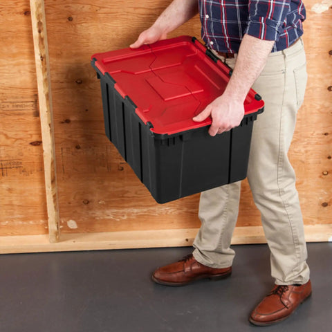 Haul Heavy Loads With Ease Using These Tough As Nails 12 Gallon Storage Totes With Secure Lids For Garage Organization Stackable Heavy Duty Crates Featuring Tie Down Grommets In A Rock Solid 12 Pack Bundle with a person holding a black and red plastic tote.