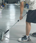 Person using Kick Ass 11 Piece Drywall Tool Set With Telescopic Extension Pole for smoothing floor surface.