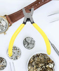 Yellow-handled watch repair tool with watch parts on a white surface.