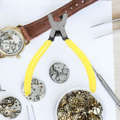 Yellow-handled watch repair tool with watch parts on a white surface.