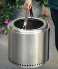 Person lifting a 19.5 inch bonfire pit using Heavy Duty Fire Pit Carrying Handle With Heat Resistant Stainless Hooks And Durable PU Strap