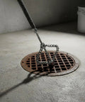 Heavy Duty Drain Chain Cleaner Steel Wire Pipe Dredger Auger Head Tool for Plumbing Lines over a drain cover.
