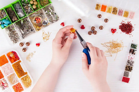 Person using pliers from 1500 Piece Silver Jump Ring Set With Lobster Clasps And Jewelry Pliers For DIY Jewelry Making Supplies Findings And Necklace Repair Beading Kit For Crafters.