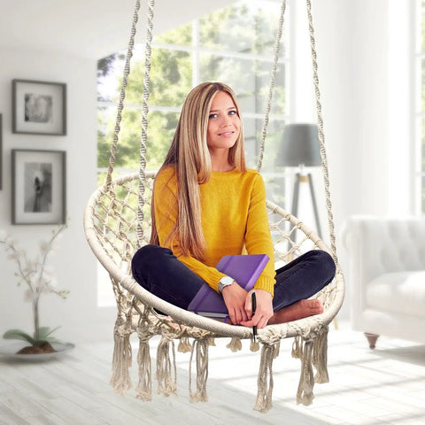 Woman sitting on Boho Macrame Swing Chair For Indoor And Outdoor Use, Durable Cotton Hanging Hammock, in modern room.