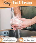Washing glass pitcher of Milk Frother With Glass Pitcher Handheld Battery Operated Foam Maker for easy cleaning at a sink.