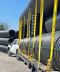 Hella Tough Ratchet Tie Down Straps With Flat Hooks securing large pipes in transport, 30ft long yellow polyester webbing.