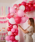 Woman arranging 66 Piece 12 Inch Hot Pink And Red Balloons Set With White And Gold Confetti For Valentines Day Decor