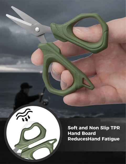 Decked-Out Fishing Tools Kit With 6.5 Inch Pliers And 4.6 Inch Scissors, Pro Grade Stainless Steel Line Cutter For Braided Line, Lanyard Included, Great For Kayak, Fly, And Freshwater Fishing; close-up of green handle scissors in hand with fisherman background