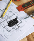 Black Stainless Steel Small Folding Butt Hinges for Cabinets and Boxes with foldable leaves, on architectural plans with tools.