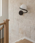 MAHGNTKCX Black Wall Sconce with Opal Glass Globe and Spiral Metal Frame mounted on a textured wall by stairs.