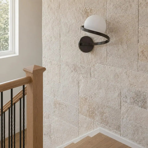 MAHGNTKCX Black Wall Sconce with Opal Glass Globe and Spiral Metal Frame mounted on a textured wall by stairs.