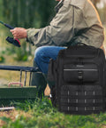 Large Fishing Backpack With Rod Holders, Waterproof 45L Tackle Box Pack beside angler fishing by the river.