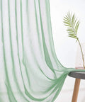 Christmas Green Semi Sheer Curtains With Linen Look draped over a table next to a decorative vase, soft fabric with subtle stripes.