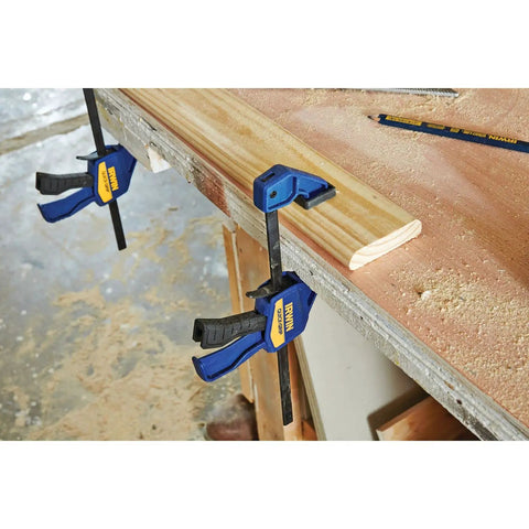 Six Inch Mini Bar Clamp Two Pack With One Hand Quick Release Trigger on wood, demonstrating firm grip and non-marring pads.