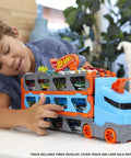 Child playing with Speedway Hauler Storage Carrier With Three 1 To 64 Scale Cars And Convertible Six Foot Drag Race Track