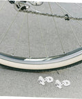 Adjustable Aluminum Alloy Bike Chain Tensioner Tool 2 Piece Set For Folding Bikes next to a bicycle wheel on pavement.