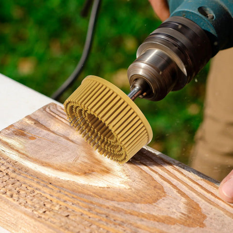 Power drill with a 2-inch beige bristle abrasive disc deburring a wooden plank.