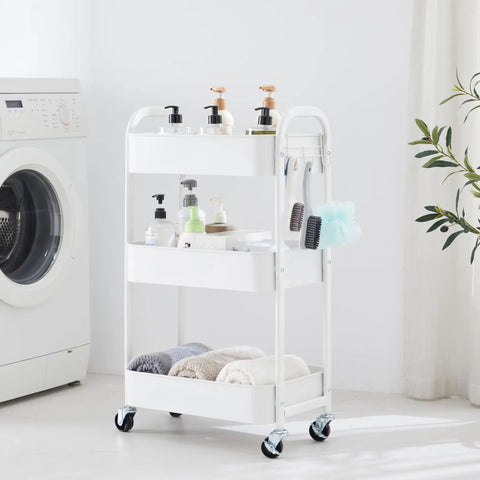 White 3-Tier Rolling Utility Cart With Caster Wheels for Kitchen and Bath next to washing machine, loaded with toiletries and towels