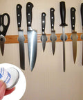 Front view of 20-pack neodymium disc magnets with double-sided adhesive securing knives to a wooden magnetic strip