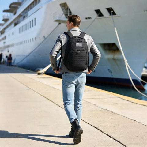 Person wearing Military Tactical Backpack With Laser Cut MOLLE Webbing, 25L EDC Daypack For Men, near a docked ship.