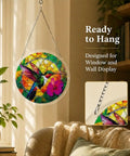 Colorful 83 Piece Little Bird Suncatcher Puzzle Kit hanging by window, features UV printed acrylic, 7.4 inches, rainbow projection.