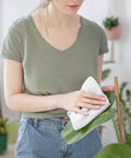 Person cleaning plant leaf with Absorbent Quick Dry Bar Mop Towels Pack Of 60, 14x17 Commercial Grade Cotton Cleaning Rags For Kitchen And Bar.