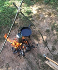 Bombproof Stainless Steel Water Bottle With Hanging Hook For Outdoor Adventures over campfire setup for cooking.