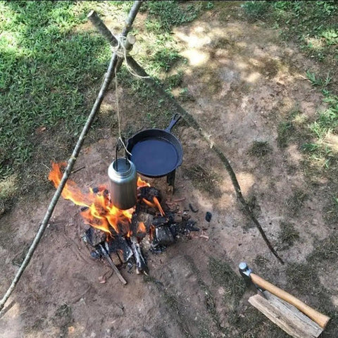 Bombproof Stainless Steel Water Bottle With Hanging Hook For Outdoor Adventures over campfire setup for cooking.