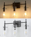 Three Light Black Vanity Light Fixture Over Mirror With Clear Glass Shades For Sleek Modern Bathroom E26 Bulb Compatible Industrial Farmhouse Style Wall Lighting, shown lit and unlit against a wall