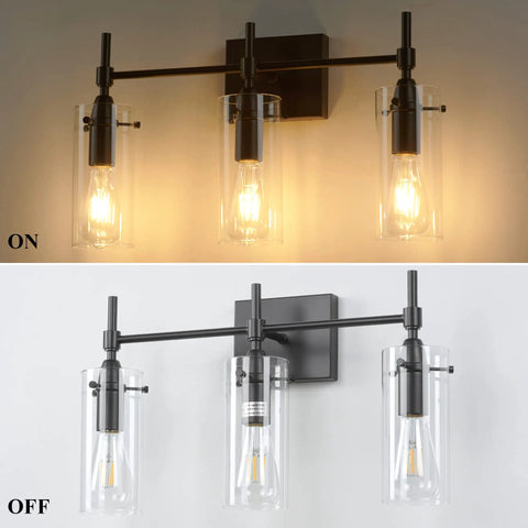 Three Light Black Vanity Light Fixture Over Mirror With Clear Glass Shades For Sleek Modern Bathroom E26 Bulb Compatible Industrial Farmhouse Style Wall Lighting, shown lit and unlit against a wall