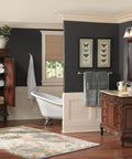 Bathroom with Weymouth 24-Inch Single Towel Bar In Chrome under framed art, near wooden vanity and tub.