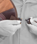 Hands adjusting shoulder strap on Adjustable Rifle And Shotgun Field Shield Recoil Pad With Leather Shirt Vest for secure fit.