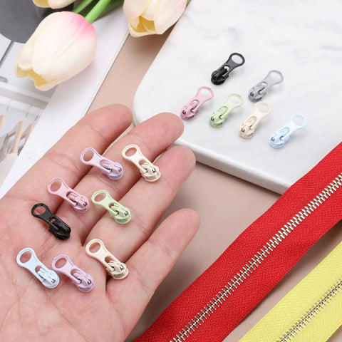 Various colored zipper sliders for 30 Pack Zipper Sliders Size Three Metal Repair Replacement With Zip Pull No Sewing Needed For Bags Wallets Jackets And Closed End Zippers Purple Great For DIY Repairs And Everyday Fixes displayed on a surface with a hand holding some