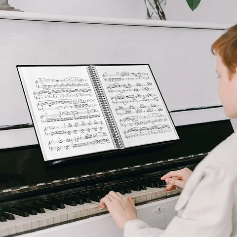 Person playing piano with open 60 Pocket Portfolio Binder With Plastic Sleeves 120 Page File Organizer for sheet music display.