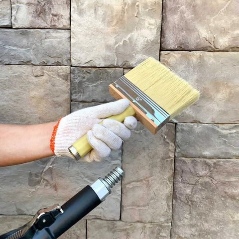 Heavy Duty 5 Inch Paint Brush With Screwed Extended Handle For Decks And Fences Stain Block Poly Bristle Blend Ideal For Walls Masonry And Large Painting Projects Pack Of 6 in hand against stone wall