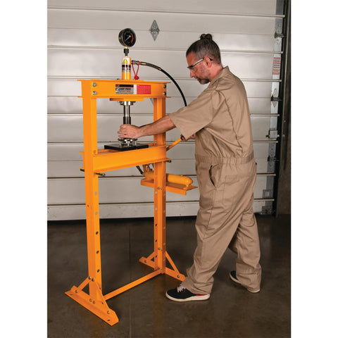 Worker operating Beefy 12 Ton Hydraulic Shop Press With Adjustable Height Remote Cylinder And Pressure Gauge For Heavy Duty Auto And Metalworking Projects Ideal For Bearing Presses Bushing Installations And Frame Repairs.