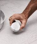 Person placing Flo Smart Water Leak Detector 3 Pack near washing machine for real-time alerts and monitoring.