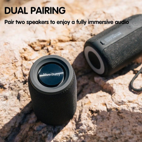 Compact Waterproof Portable Bluetooth Speaker That Goes Hard With Deep Bass, Dual Pairing, FM Radio, USB And AUX Input on rocks