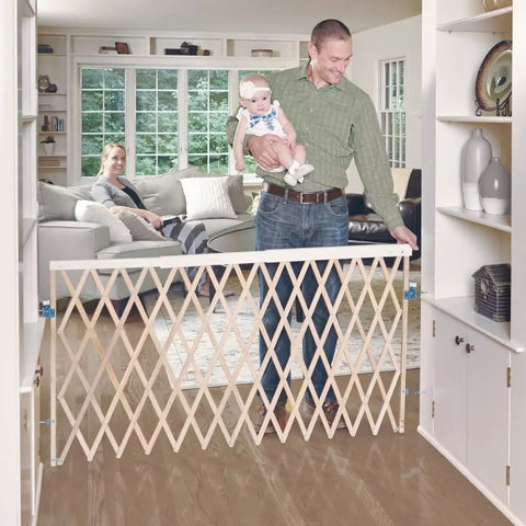 Extra Wide Swing Out Wooden Baby Gate Fits Twenty Four To Sixty Inch Openings Super Secure With Safety Latch And Hardware Mount Thirty Two Inches Tall Sustainable Hardwood For Homes With Kids And Pets shown installed in a bright living room with a dad holding a baby and mom watching on sofa.