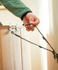 Hand installing Universal TV Security Straps Four Pack For Wall Furniture And Anti Tip Configurations on a light wooden cabinet.