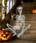 3 Foot Full Body Halloween Skeleton Decoration for Party and Haunted House seated on steps with carved pumpkin nearby