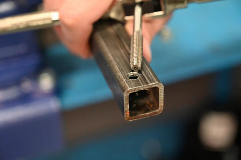 Badass Metric Tap And Drill Set For Precise Thread Cutting High Carbon Steel Plug Tap With Matching Bit Killer Combo Pack For Garage Builds And Machine Shop Jobs Built Solid To Knock Out Threads Without Breaking A Sweat Sure Fire Workshop Powerhouse on metal workpiece being threaded with tap.