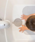 Premium Soft Silicone Bathtub Drain Stopper With Super Strong Suction Cup locks water in fast, gray tub plug in use with toddler hands.
