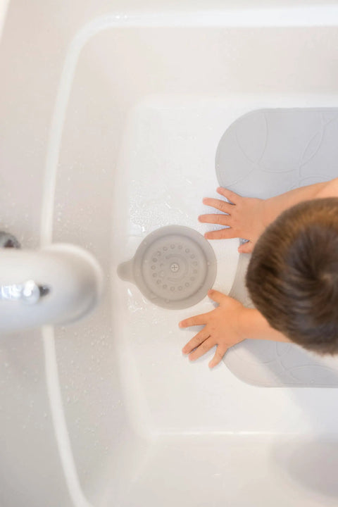 Premium Soft Silicone Bathtub Drain Stopper With Super Strong Suction Cup locks water in fast, gray tub plug in use with toddler hands.