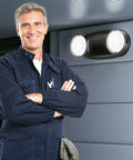 Installer with Six Pack Round LED Emergency Light With Battery Backup Black Dual Adjustable Heads mounted on wall