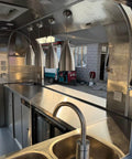 Interior view of Rock Solid Heavy Duty Mobile Coffee Concession Cart With Spacious Storage Compartments showing stainless steel surfaces and lighting.