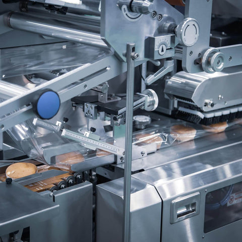 Industrial machinery close-up with food packaging process in operation.