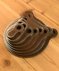 Half Inch AR500 KYL Gong Target Set 1 In To 8 In Eight Pack For Progressive Accuracy Training laying stacked on wooden surface